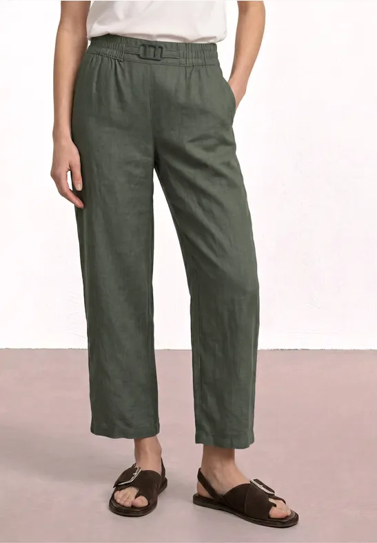 Loszittende damesbroek in olijfgroen met hoge taille, steekzakken en bruine sandalen.