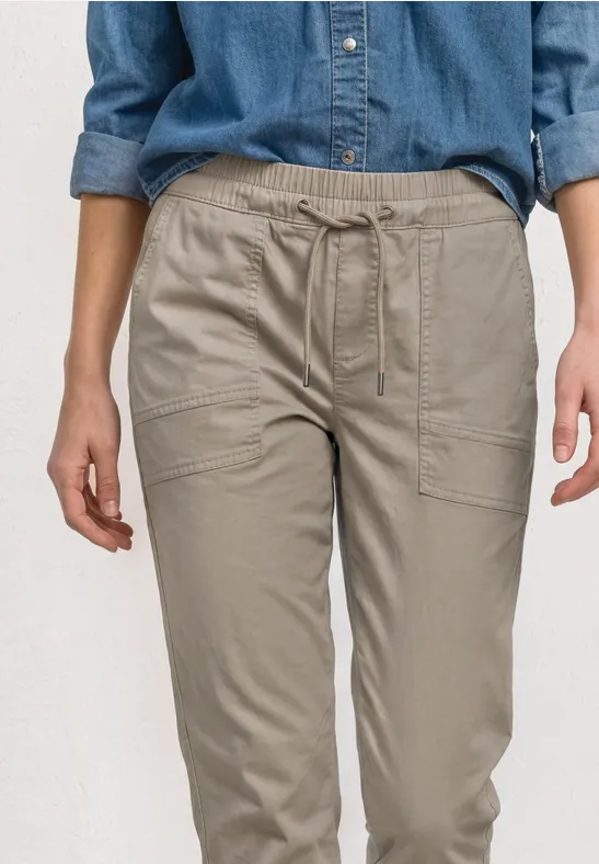 Een persoon draagt een comfortabele beige cargobroek van licht materiaal met zijzakken.