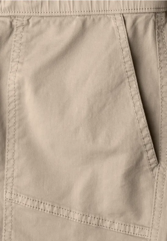 Close-up van een beige broek met zak en stiksels.