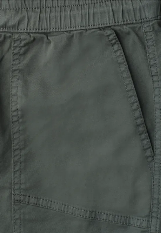 Close-up van een donkergroene broek met elastische taille en zijzak.
