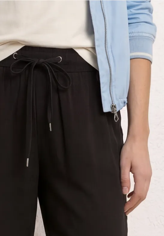 Close-up van persoon in zwarte joggingsbroek en lichtblauw jack.