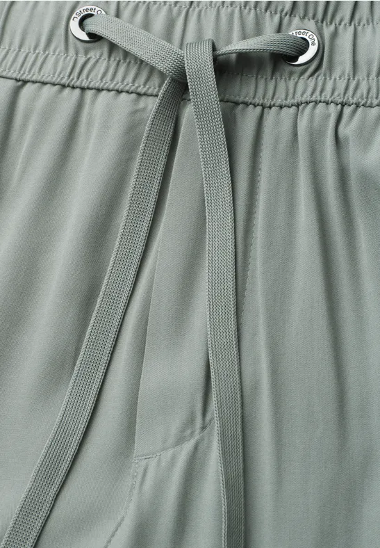 Detailaufnahme einer graugrünen Hose mit Kordelzug und Gummibund
