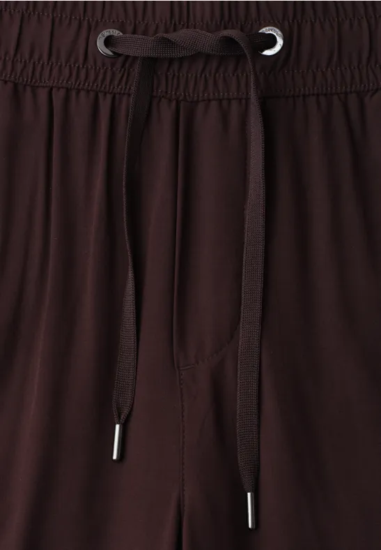 Bruine broek met elastische taille en trekkoorden, close-up van het taillegebied.