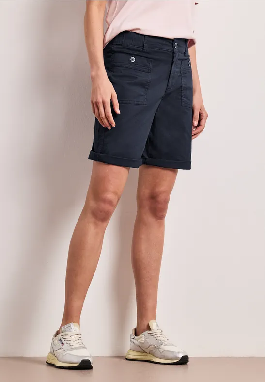 Donkerblauwe bermudashorts met witte sneakers gedragen door een model