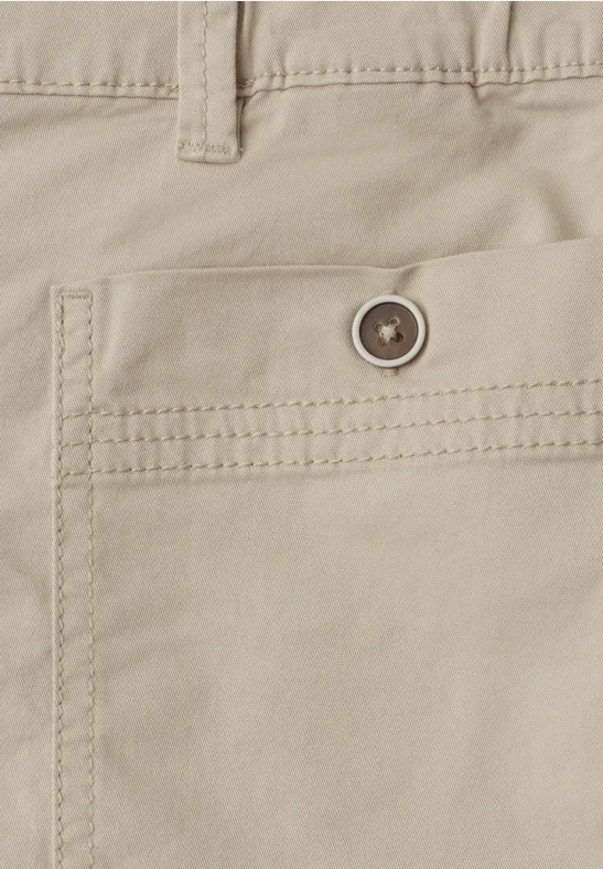 Close-up van een beige katoenen broek met een knoopsluiting op de achterzak en zichtbare stiksels.