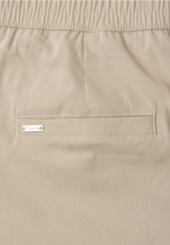 Beige Hose mit elastischem Bund und schmales Paspeltasche mit Metall-Label.