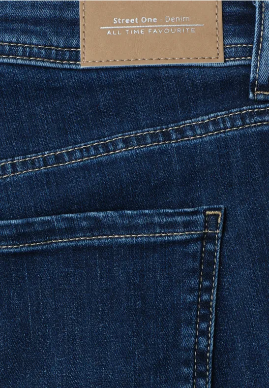 Nahaufnahme einer dunkelblauen Jeans mit Gesäßtasche und braunem Markenlederlabel am Bund.