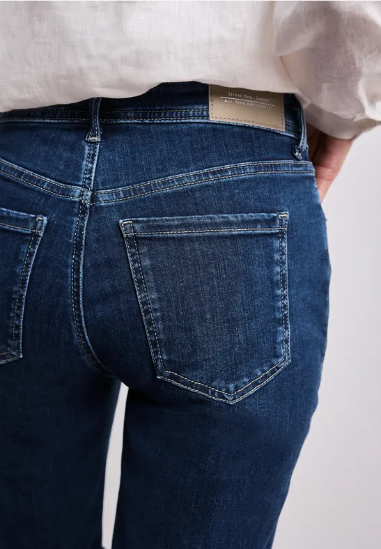 Dunkelblaue Jeans mit zwei aufgesetzten Gesäßtaschen, kombiniert mit einem hellen Leinenhemd.