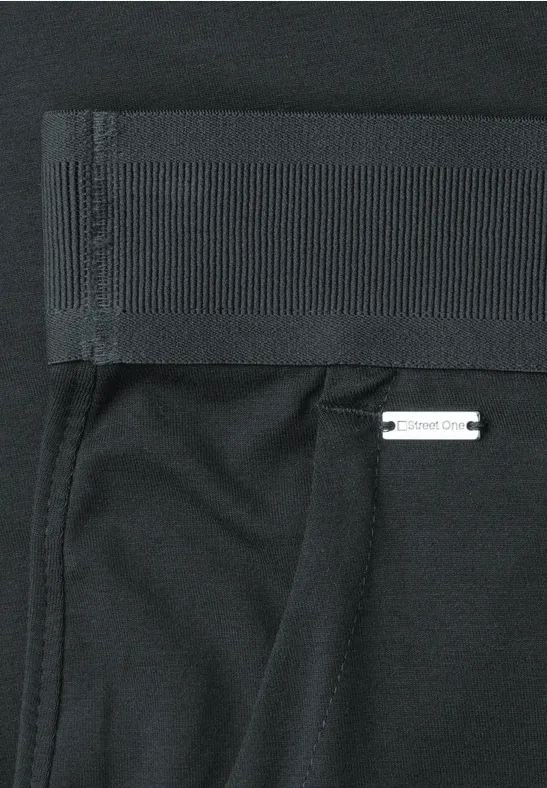 Schwarze Sporthose mit breitem Bund, Seitentasche und kleinem weißen Etikett am Saum.