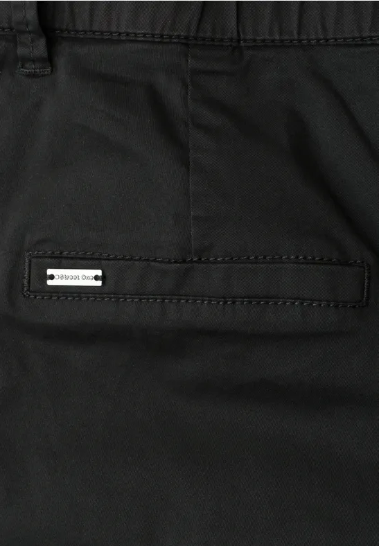 Nahaufnahme einer schwarzen Hose mit Gesäßtasche und kleinem Metall-Badge.