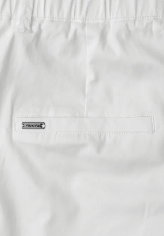 Weißes Kleidungsstück mit Gesäßtasche und kleinem Metall-Label auf der Rückseite.