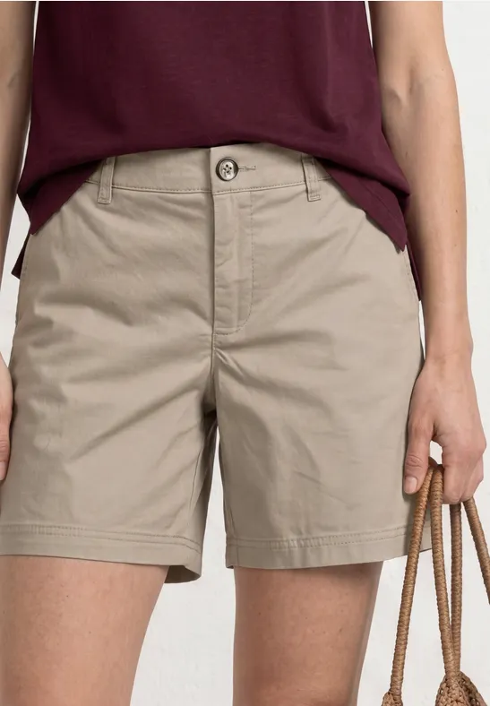 Vrouw draagt kaki short en bordeauxrood t-shirt, houd een tas met touwhandvatten vast.