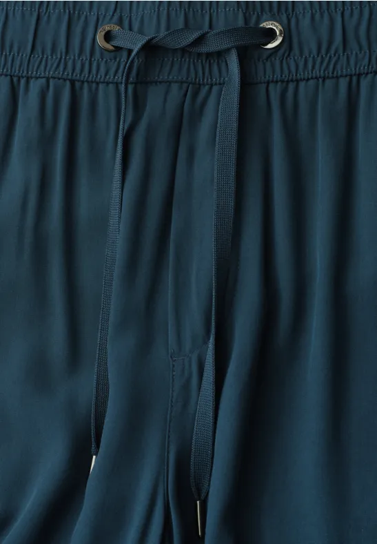 Close-up van een donkergroene broek met elastische tailleband en trekkoord.