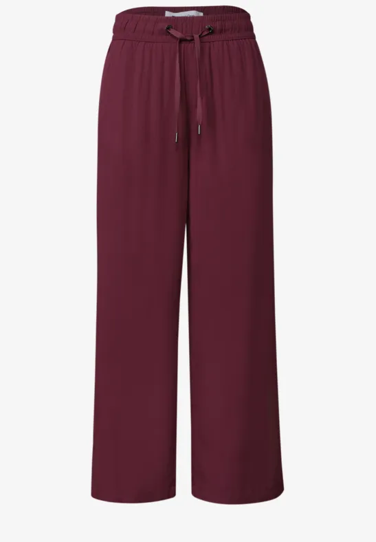 Bordeauxrote, weite Stoffhose mit elastischem Bund und Kordelzug.