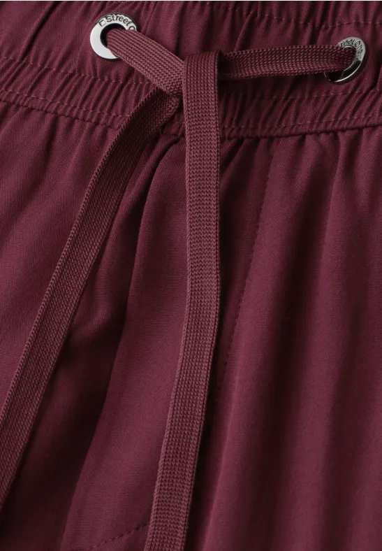 Nahaufnahme einer burgunderfarbenen Hose mit Tunnelzug und Elastikbund.