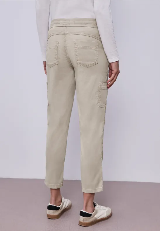Beige Cargohose mit Taschen, knöchellang, Slim-Fit, kombiniert mit beigen Slip-On-Schuhen.