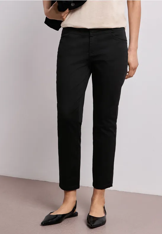 Schwarze, gerade geschnittene Damenhose kombiniert mit spitzen Ballerinas und einem hellen Oberteil