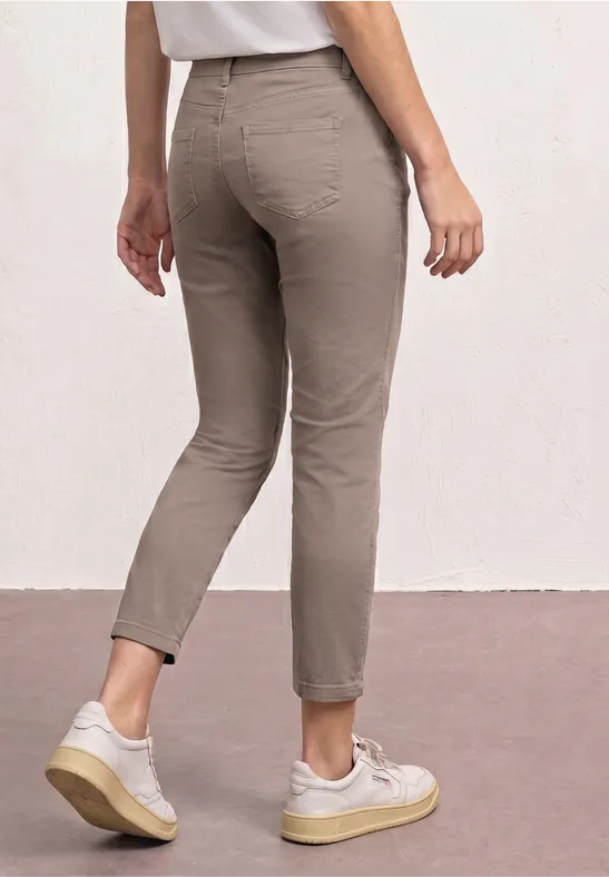 Rückansicht einer Person in taubenfarbener, knöchellanger Hose und weißen Sneakern.