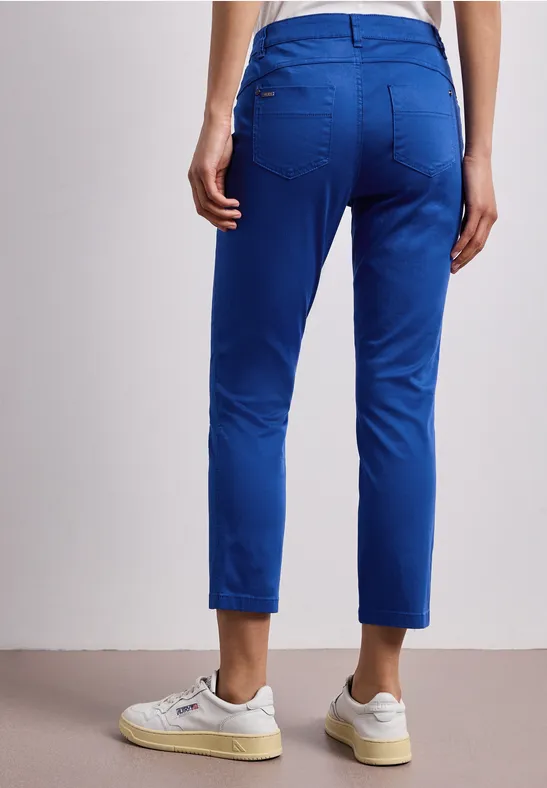 Een persoon van achteren draagt een blauwe broek en witte sneakers.