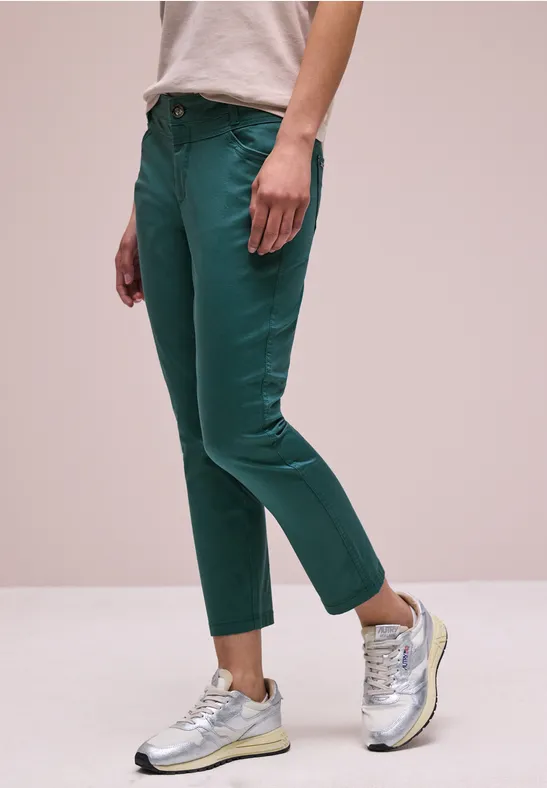 Grüne schmale 7/8-Hose, silberne Sneaker und helles Oberteil.