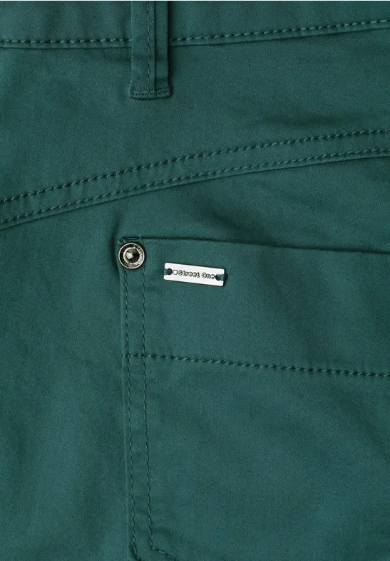 Grüner Hosen-Taschenbereich mit Ziernaht, Metallknopf und kleinem Etikett.