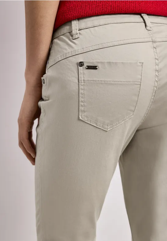 Rückansicht einer Person in beigen Hosen mit rotem Oberteil, Fokus auf Gesäßtasche.