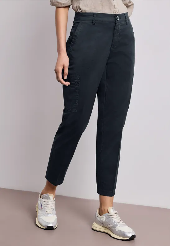 Schlanke schwarze 7/8-Hose kombiniert mit weißen Sneakern.