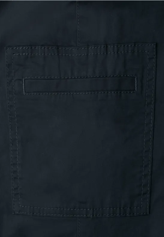 Detail eines dunklen Kleidungsstücks mit eingenähtem, quadratischem Taschenfach.