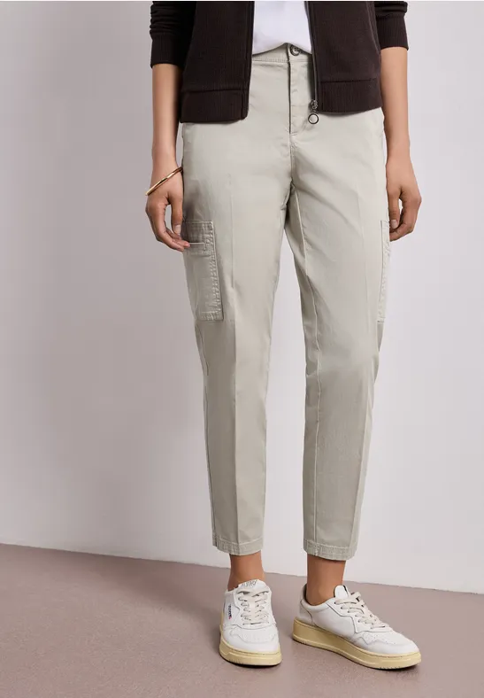 Beige Cargohose mit aufgesetzten Taschen, kombiniert mit weißen Sneakern.