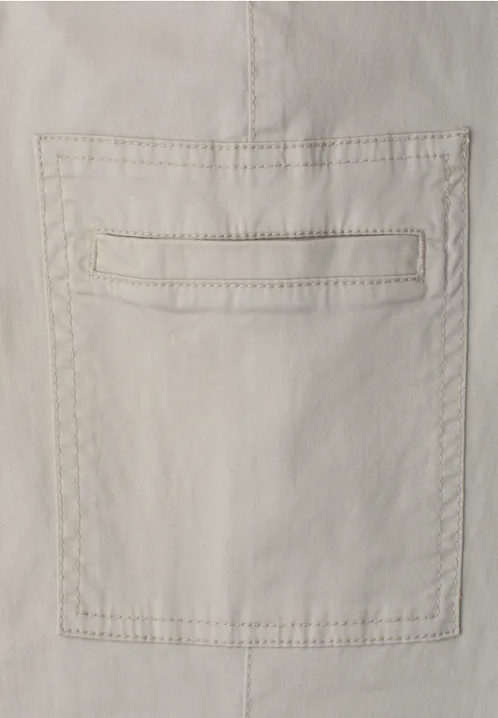 Beige Baumwollstoff mit aufgesetzter Tasche und gesteppten Ziernähten.