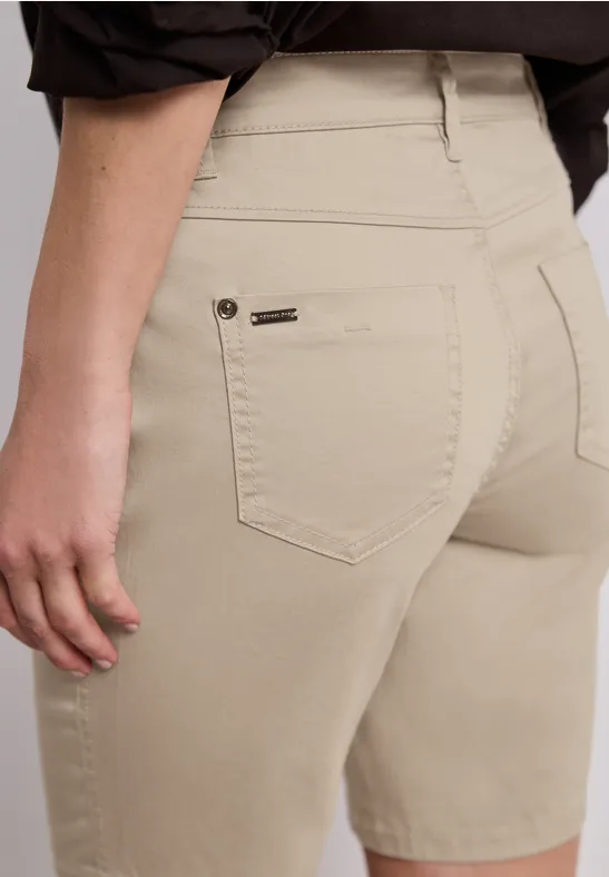 Iemand draagt een beige bermudashort en zwart shirt, achterkant met zijzak zichtbaar.