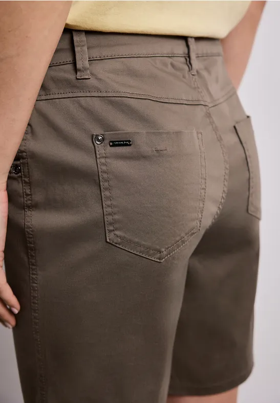 Rückenansicht einer Person in olivgrünen Shorts und hellem Oberteil.