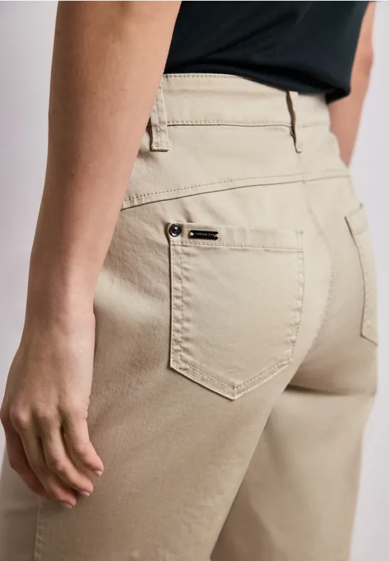 Person von hinten in beigefarbenen Hosen mit Gürtelschlaufen und Gesäßstaschen.