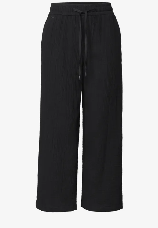 Schwarze, weit geschnittene Hose mit Elastikbund und Kordelzug, strukturierter Stoff, gerade Beinform.