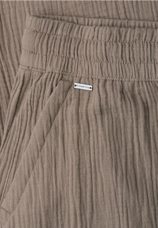 Close-up van taupekleurige, geribde katoenen broek met elastische taille en zijzak.