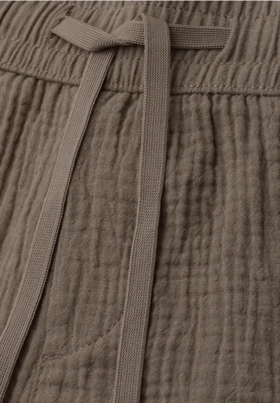 Pantalon en gaze de coton taupe, taille élastique et cordon, tissu léger et texturé.
