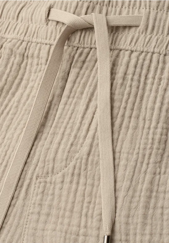 Beige Baumwollhose mit gerippter Struktur, Tunnelzug und dezenter Tasche.