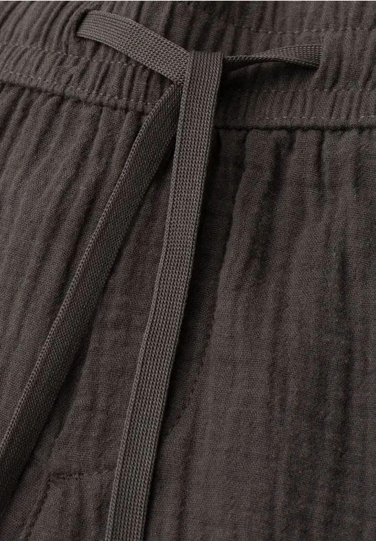 Nahaufnahme einer dunkelgrauen Leinenhose mit Kordelzug und feiner Webstruktur.