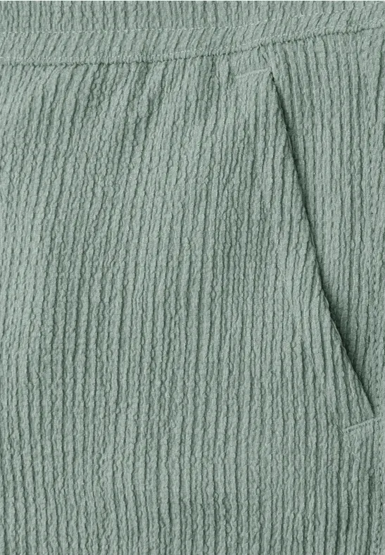 Nahaufnahme einer mintgrünen, texturierten Stoffhose mit Taschennaht