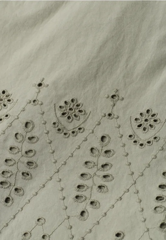 Licht linnen stof met fijne, symmetrische bloemen- en bladborduursels.