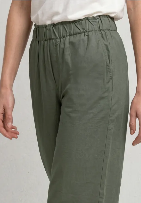 Eine Person trägt olivgrüne Baumwollhose mit elastischem Bund und seitlichen Taschen.