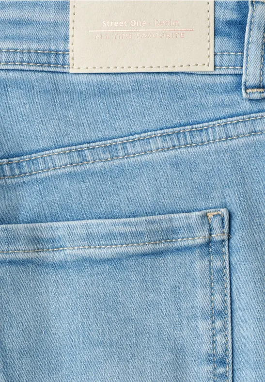 Close-up van een lichtblauwe spijkerbroek met achterzak en merklabel zichtbaar.