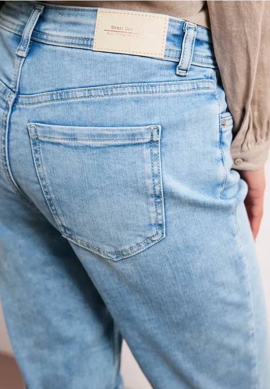 Achteraanzicht van persoon in lichtblauwe spijkerbroek, zichtbare achterzak en taillelabel.