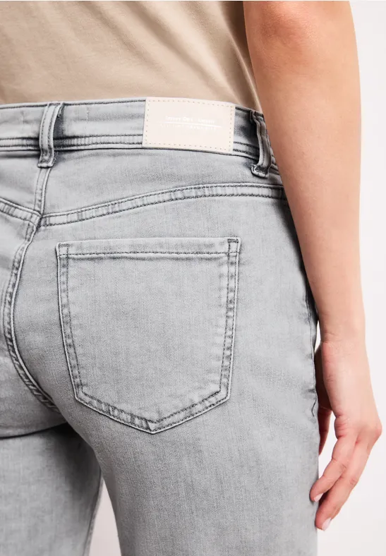 Nahaufnahme einer Person in hellgrauen, eng sitzenden Jeans mit Gesäßtasche.