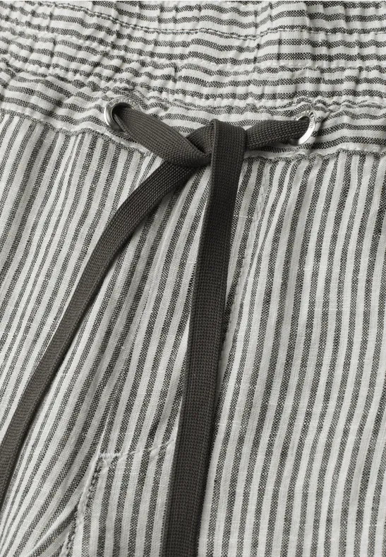 Close-up van een grijze broek met witte strepen en zwarte koordsluiting in de elastische taille