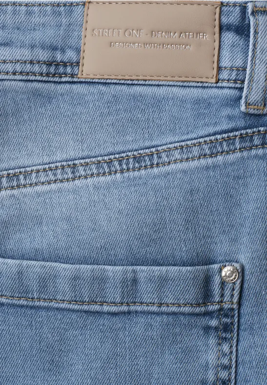 Nahaufnahme einer blauen Jeans mit Fronttasche, Metallniete und Lederetikett am Bund