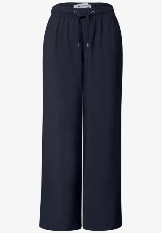 Schwarze, lockere, weite Hose mit elastischem Bund und Kordelzug, aus fließendem Material.