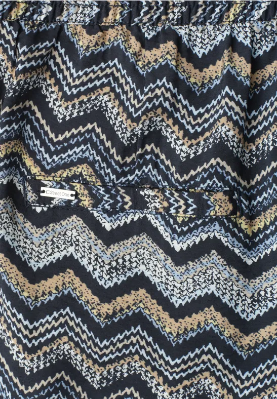 Strickstoff mit blau-weiß-beige Zickzack-Muster und aufgesetzter Reißverschlusstasche.