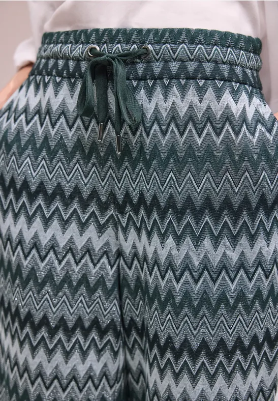 Broek met groen-grijs zigzagpatroon, elastische taille en trekkoord.