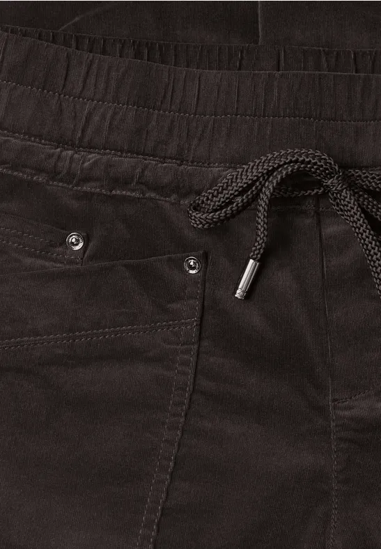 Schwarze Samthose mit Gummibund, Kordelzug, seitlichen Taschen und Metallösen als dezentes Detail.